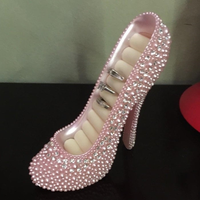 This elegant pink high-heel shoe ring holder, adorned with pearls and crystals, stylishly organizes and displays rings while adding a glamorous touch to your space