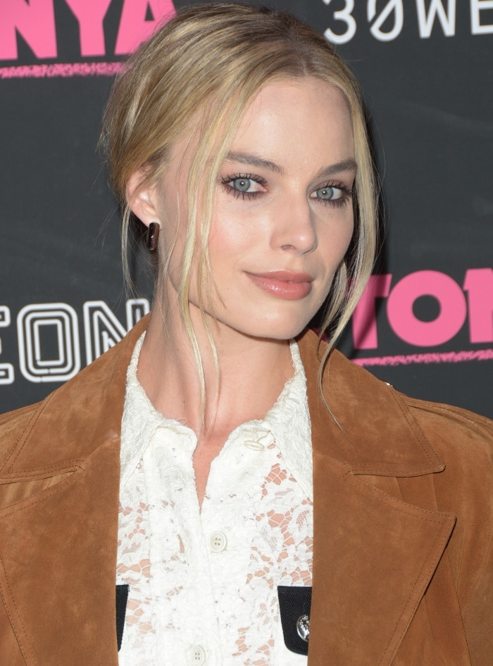 Margot Robbie wears her hair in a chic updo with face-framing strands, paired with soft makeup that enhances her natural glow
