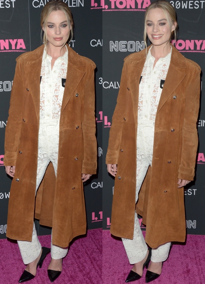 Margot Robbie layers a suede brown coat over a white lace blouse and matching lace pants, finishing her Calvin Klein 205W39NYC look with sleek black pumps