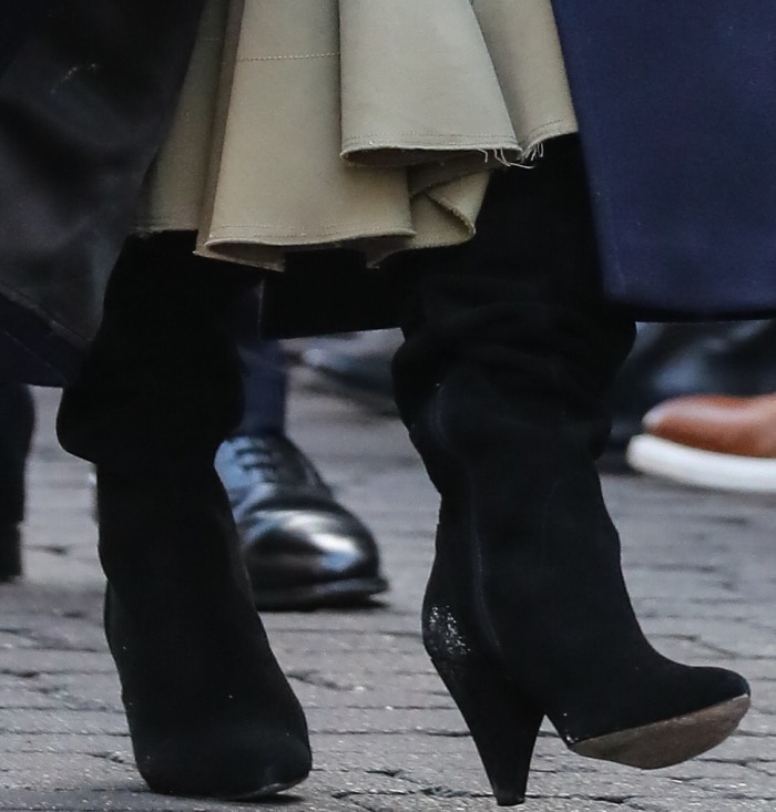 Meghan Markle steps out in black suede KG Kurt Geiger “Violet” over-the-knee boots, featuring a sleek pointed toe and sculptural cone heels that add modern polish to her winter ensemble