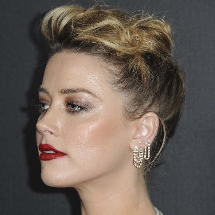 Amber Heard wearing a sculpted updo, crimson lipstick, and mismatched Anita Ko diamond earrings