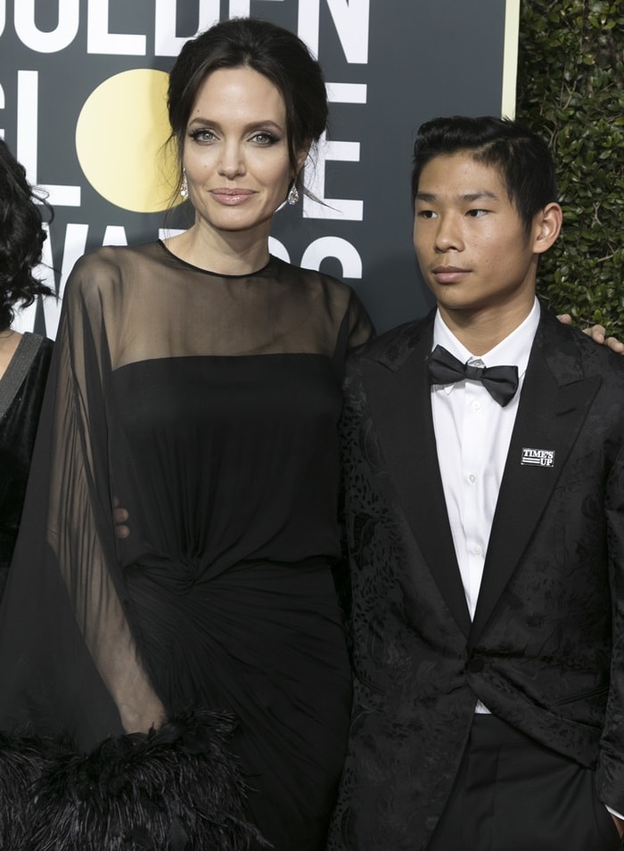 Angelina Jolie arrived at the 2018 Golden Globe Awards with her son Pax Jolie-Pitt, pairing a sheer black Atelier Versace gown with understated diamond earrings and soft Old Hollywood beauty styling