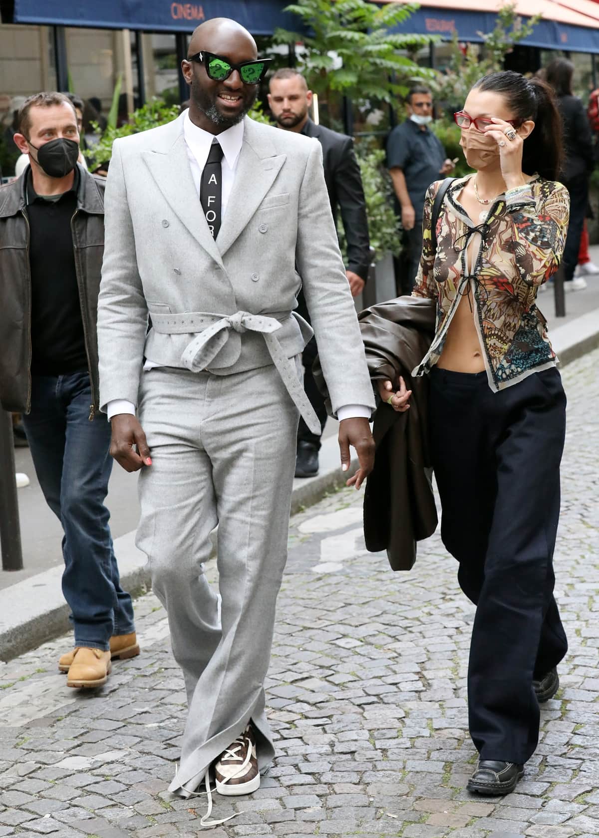 Fashion visionary Virgil Abloh, in a distinctive suit, and model Bella Hadid, in her signature street style, are seen strolling in Saint Germain, Paris, on June 24, 2021, showcasing their contrasting yet influential footwear choices