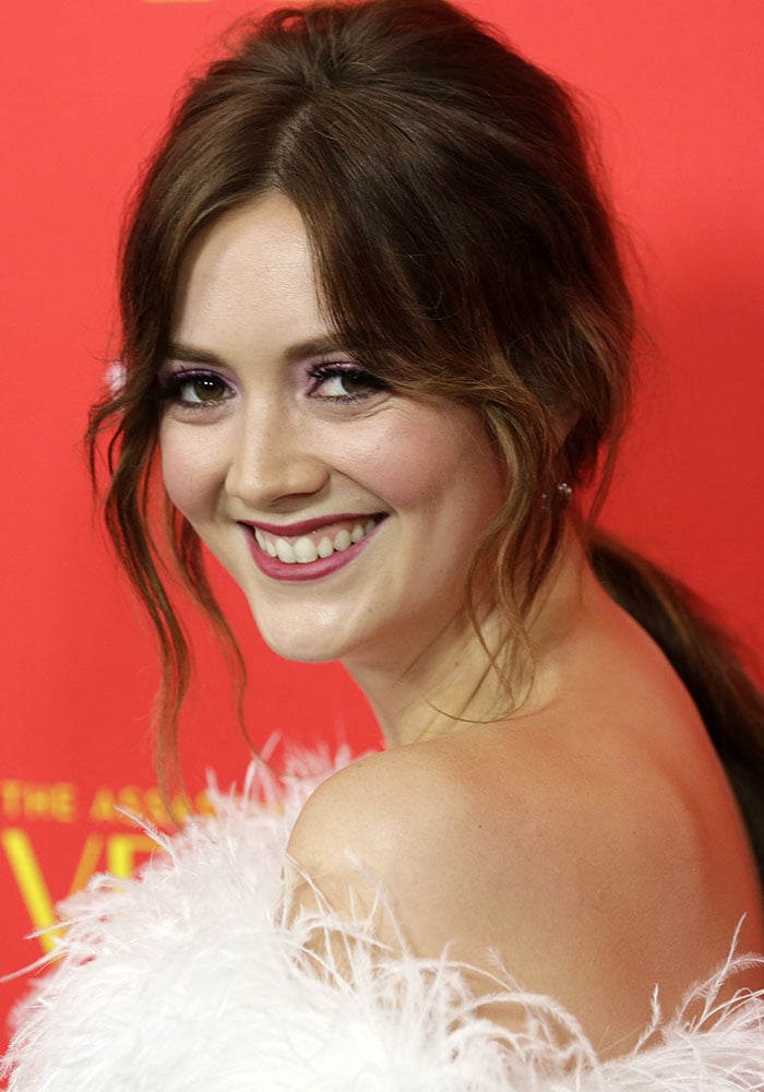 Billie Lourd smiles for the cameras at FX’s The Assassination of Gianni Versace: American Crime Story premiere at the ArcLight Hollywood on January 9, 2018, wearing a feather-trimmed off-the-shoulder gown that nods to vintage glamour