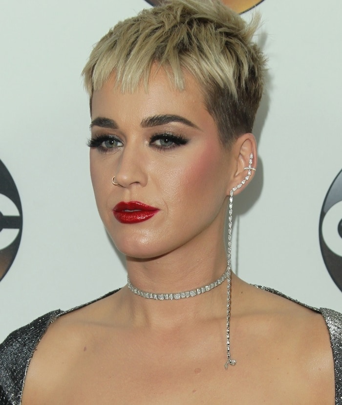 Katy Perry paired a platinum pixie cut and glossy red lips with a dramatic diamond ear cuff that echoed the futuristic shimmer of her metallic evening look