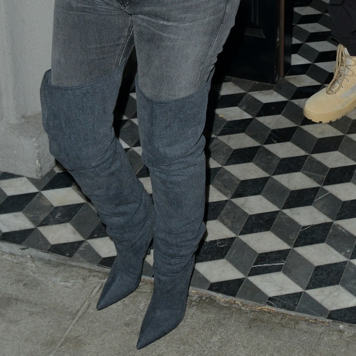 Kim Kardashian wears charcoal stretch over-the-knee boots with pointed toes and slim stiletto heels, creating a streamlined, sock-like silhouette