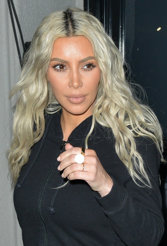 Kim Kardashian debuted her platinum blonde hair in loose, center-parted waves, pairing the bold look with a sleek black zip-up for a casual yet striking appearance