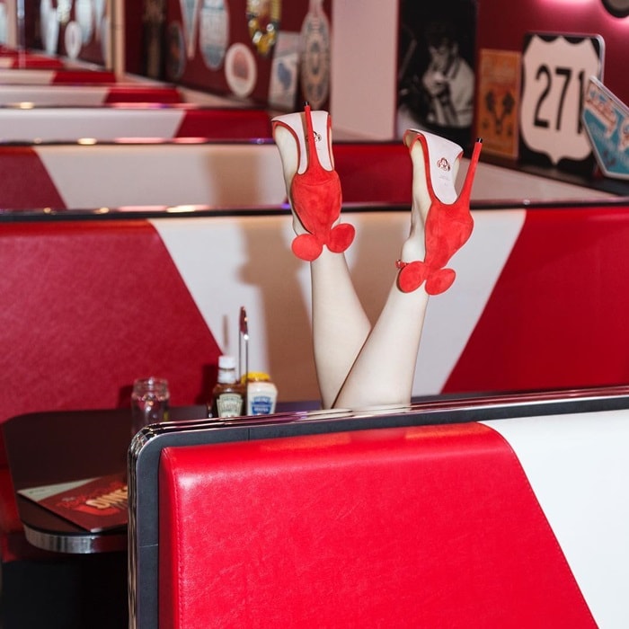 Playful and eye-catching, these red Oscar Tiye 'Minnie' heels with signature mouse-ear details bring a whimsical flair to a retro diner setting