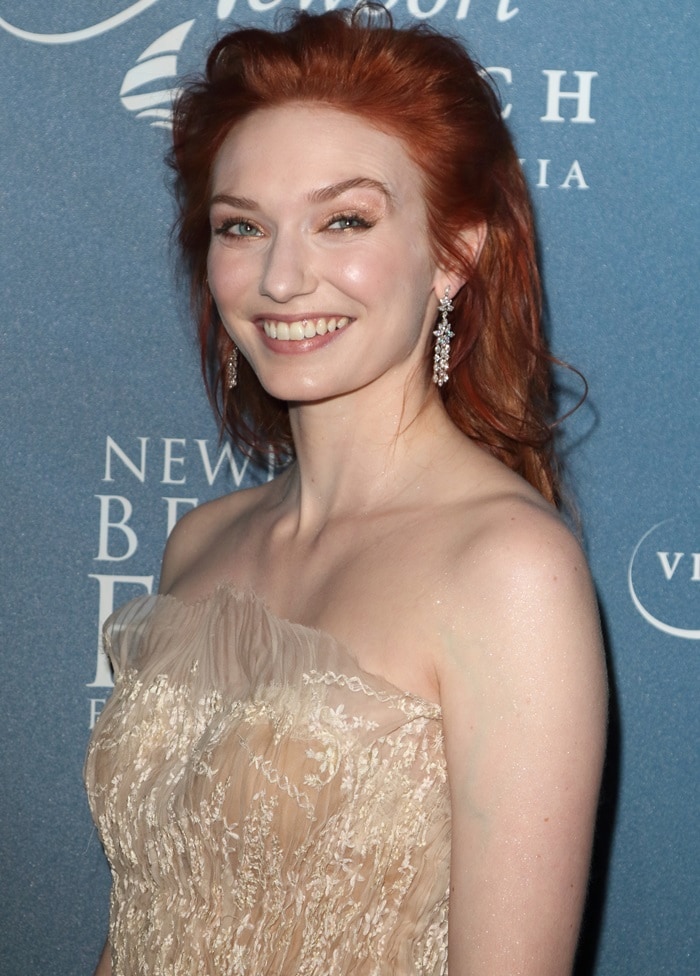 Eleanor Tomlinson showcases her radiant red hair and sparkling hazel eyes in a strapless, embroidered nude gown that highlights her ethereal beauty