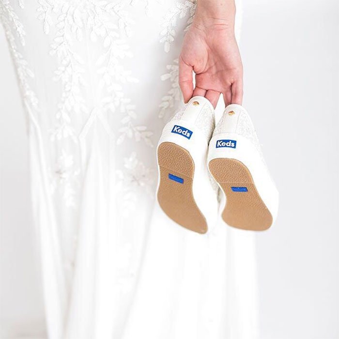 Held against a lace wedding gown, the blue Keds heel tabs quietly reinforce the collection’s “something blue” concept while highlighting the comfort-first approach that helped bridal sneakers move into the mainstream
