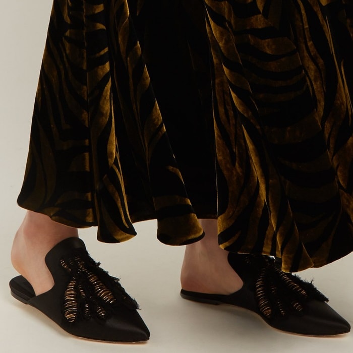 These black satin 'Ragno' slipper shoes are embroidered in Italy with a bronze bee motif and edged with frayed crepe to heighten the handmade feel.