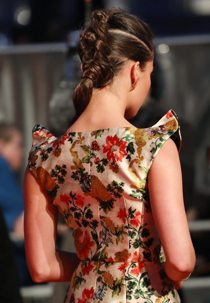 A braided ponytail adds a sleek, modern twist to the back view of her structured gown