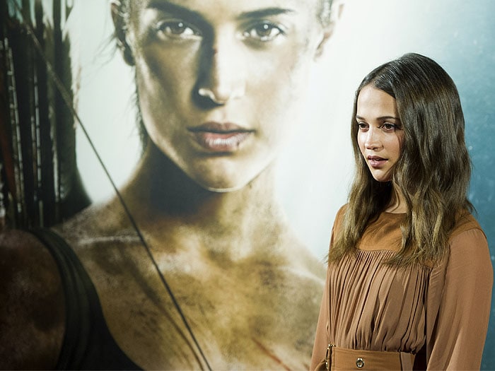 Vikander poses in front of her fierce Lara Croft poster backdrop, echoing the film’s adventurous tone