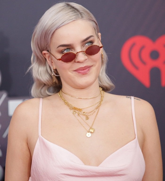 The English singer balanced her blush satin slip dress with delicate gold jewelry and narrow tinted shades that echoed the understated glamour of late-2010s red-carpet styling