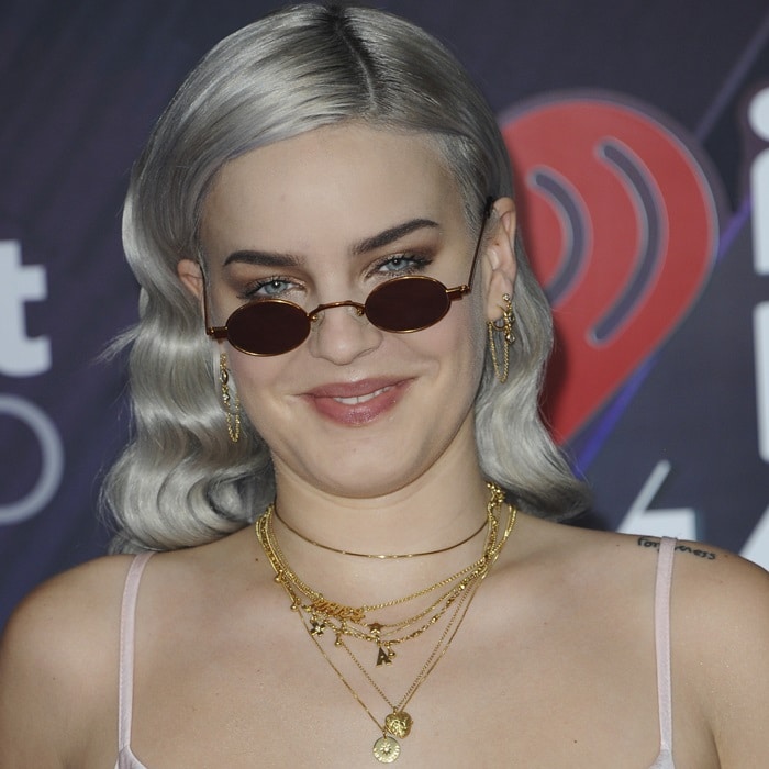 Anne-Marie paired tiny oval Roberi Fraud sunglasses with layered gold necklaces and softly waved silver hair for a cool, retro-inspired finish at the 2018 iHeartRadio Music Awards