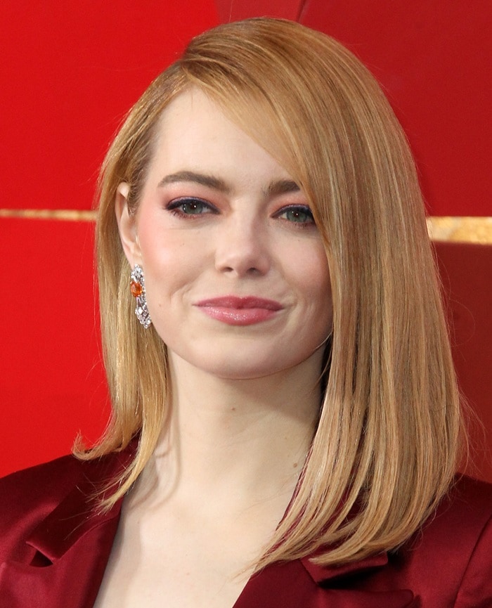Emma Stone showcases soft glam makeup and sleek, side-parted hair while attending the 2018 Academy Awards