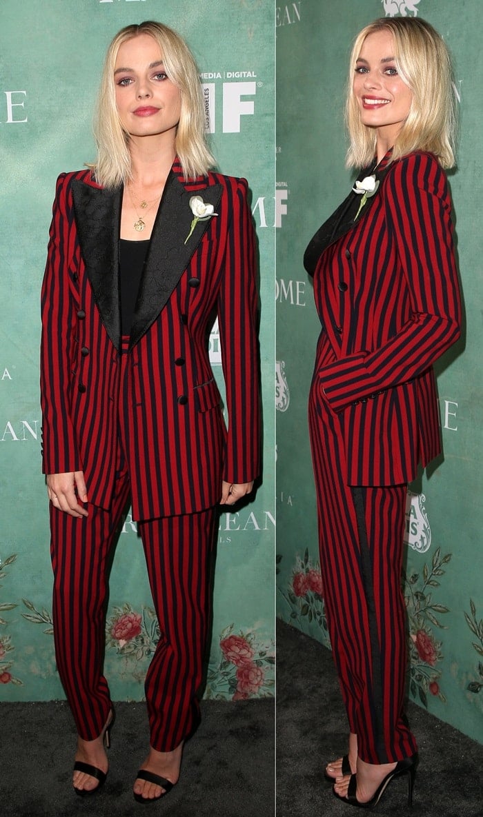 Margot Robbie puts a modern spin on tailoring in a red-and-black striped Dolce Gabbana suit, styled with a sleek bodysuit and minimalist Jimmy Choo sandals