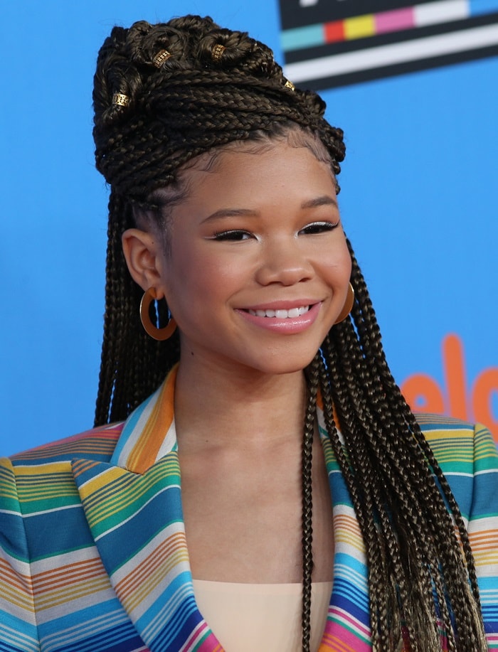 Storm Reid shines in a colorful Moschino striped blazer at the 2018 Nickelodeon Kids' Choice Awards, paired with bold braids and hoop earrings for a playful yet stylish look