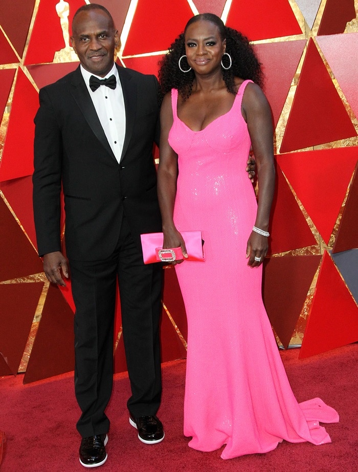 Viola Davis and her husband Julius Tennon at the 2018 Oscars, where Tennon looked sharp in a classic black tuxedo styled with glossy black sneakers featuring bold white soles, complementing Davis’s vibrant pink Michael Kors gown