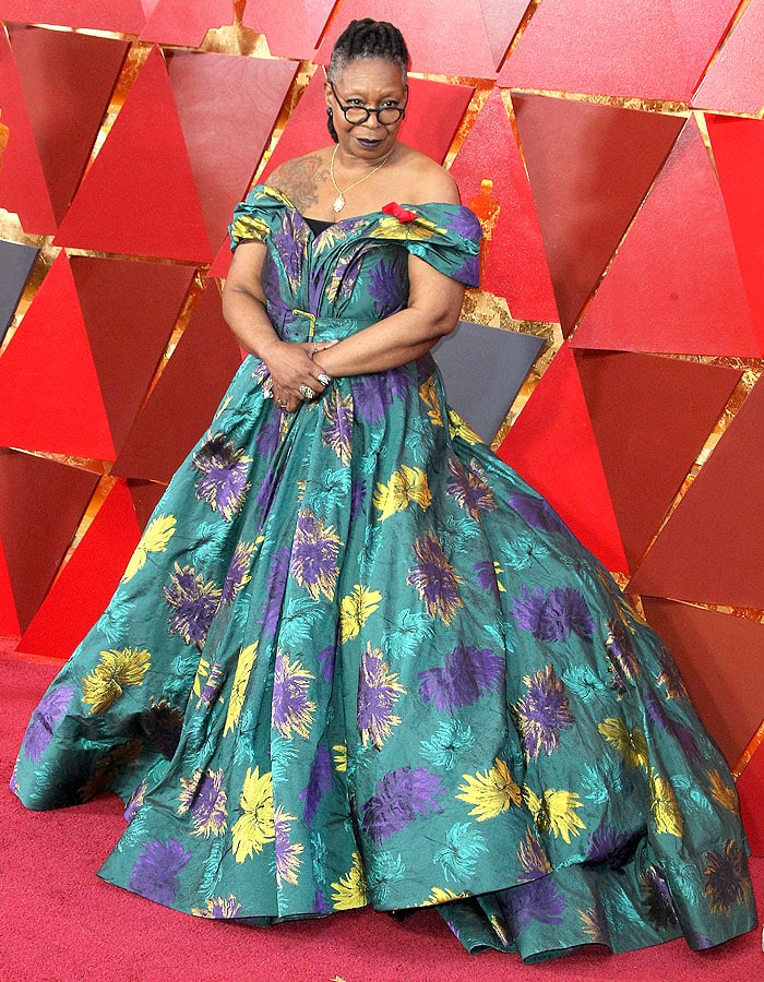 Whoopi Goldberg's off-the-shoulder dress, adorned with yellow and purple florals and a red ribbon in support of The Elizabeth Taylor AIDS Foundation, revealed her tattoos and exuded a royal attitude