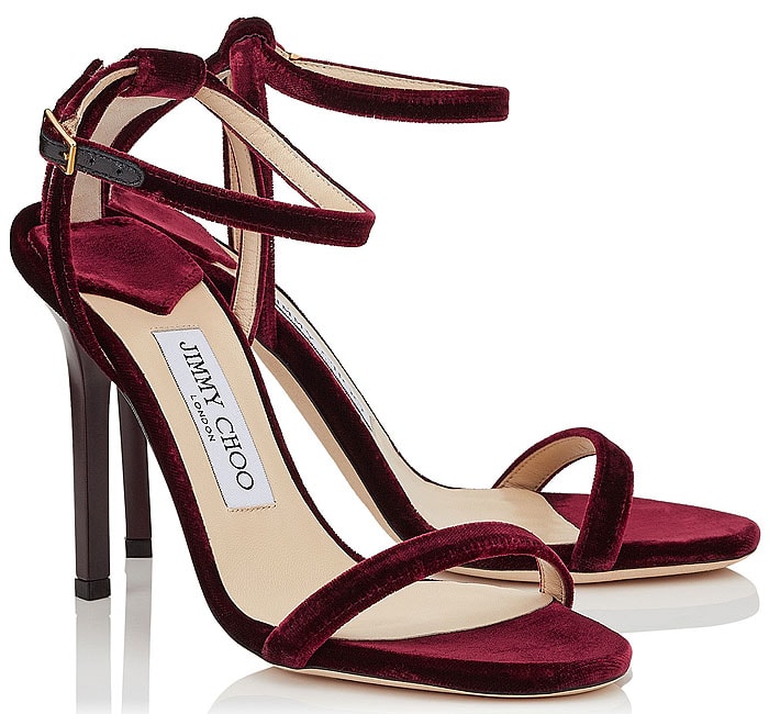 Jimmy Choo “Minny” Velvet Sandals in Bordeaux — A barely-there stiletto design with slim toe and ankle straps, crafted in plush velvet for a rich red-carpet finish