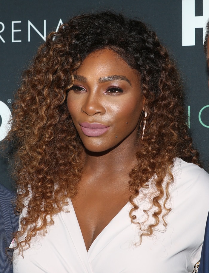 Serena Williams radiates elegance with her voluminous curls, soft pink makeup, and sparkling drop earrings