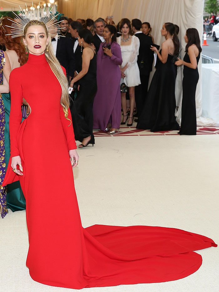 Amber Heard wearing a Carolina Herrera red long-sleeved open-back gown, an Apatico zip-tie halo, Jennifer Meyer jewelry, and Brian Atwood heels at the 2018 Met Gala