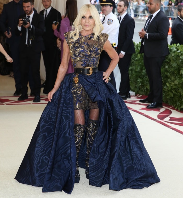 Donatella Versace in an embroidered mini dress styled with matching knee boots and a black belt