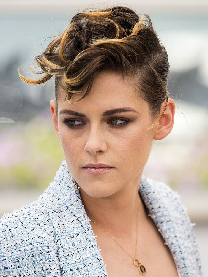 Kristen Stewart showcases an edgy, tousled updo with blonde highlights, complemented by a delicate gold pendant necklace