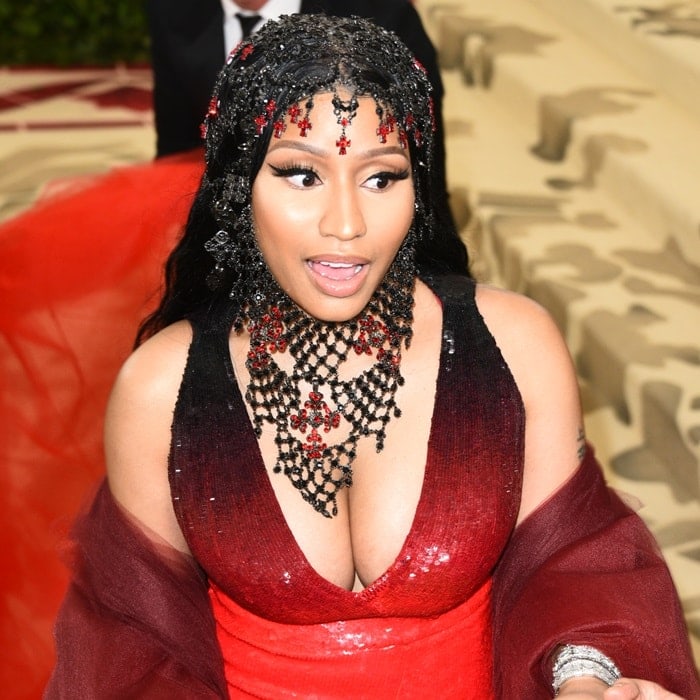 Nicki Minaj makes a dramatic statement in a plunging ombré-red Oscar de la Renta gown, topped with a black-and-red rosary-inspired headpiece and ornate beaded jewelry