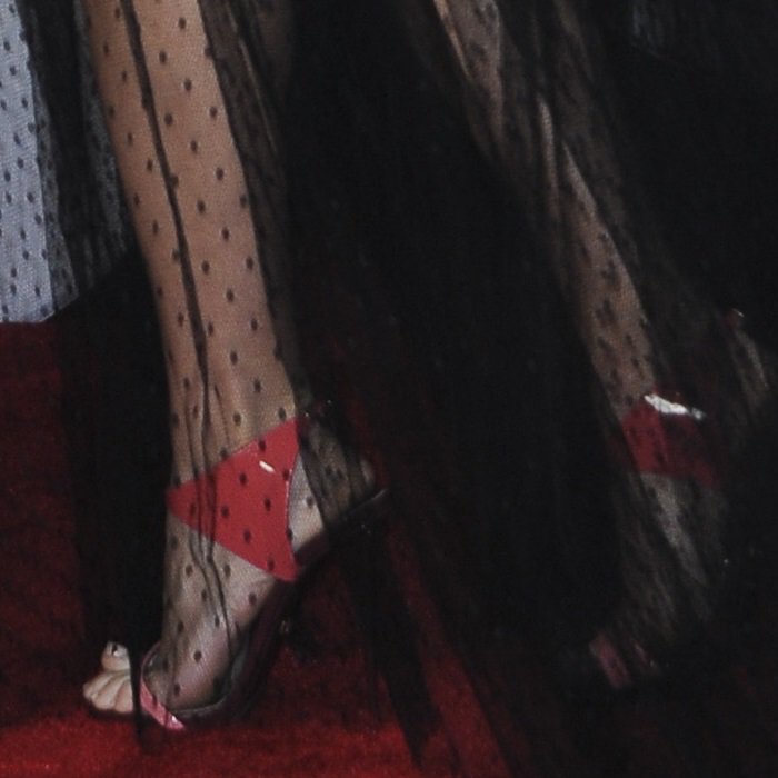 A flash of glossy coral patent leather peeked through Carrie Underwood’s sheer polka-dot tulle skirt, adding a bold jolt of color against the black MSGM dress