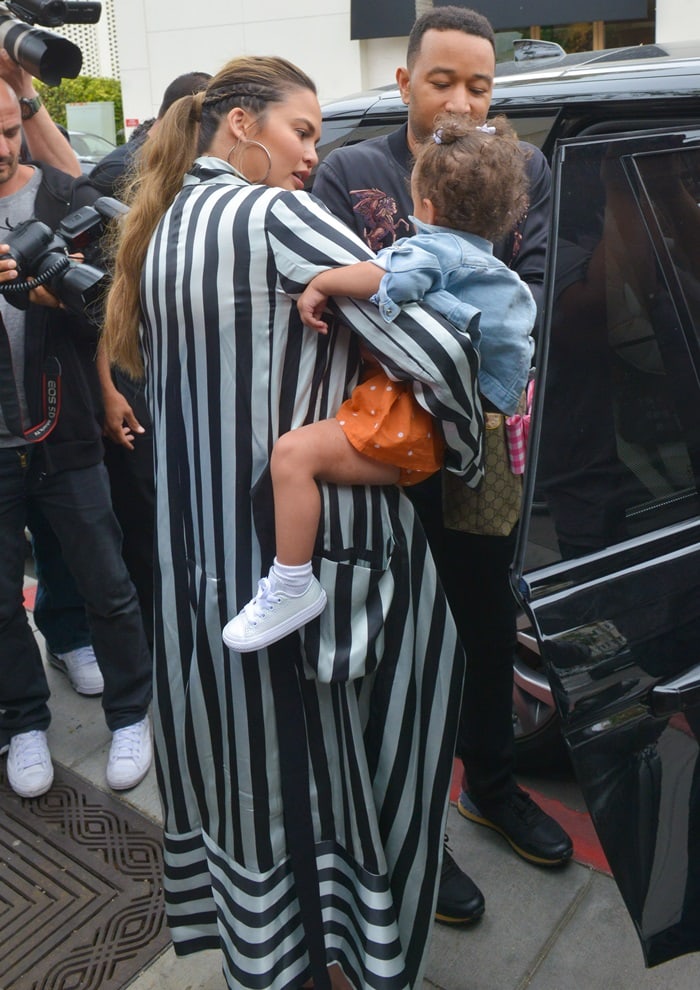 Stepping curbside with John Legend, Teigen’s graphic striped robe coat brings structure and movement to an otherwise streamlined daytime look