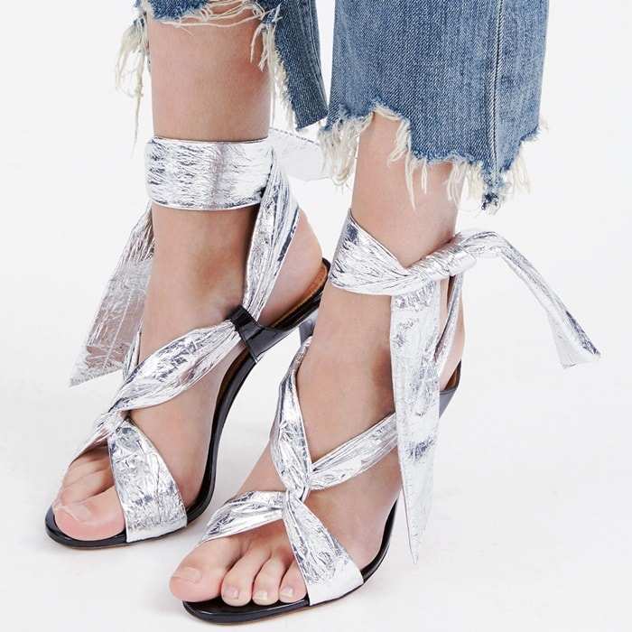 IRO’s silver “Pipa” sandals combined crinkled metallic leather with dramatic wraparound ankle ties, creating a barely-there evening silhouette balanced by slim black stiletto heels and minimalist crossover straps