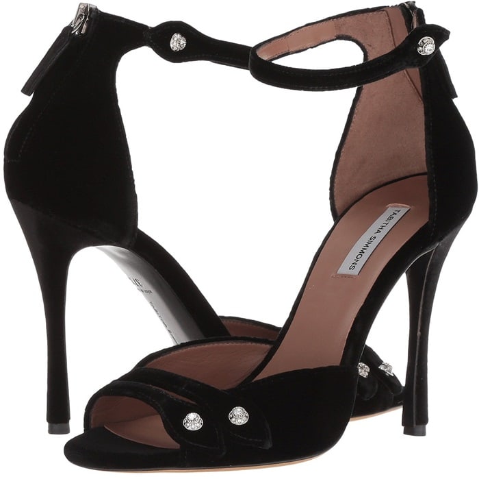 A sleek take on evening elegance, the black velvet “Mali” sandals feature a slim ankle strap, softly curved toe band, and signature Swarovski crystal buttons that add subtle sparkle against the plush texture