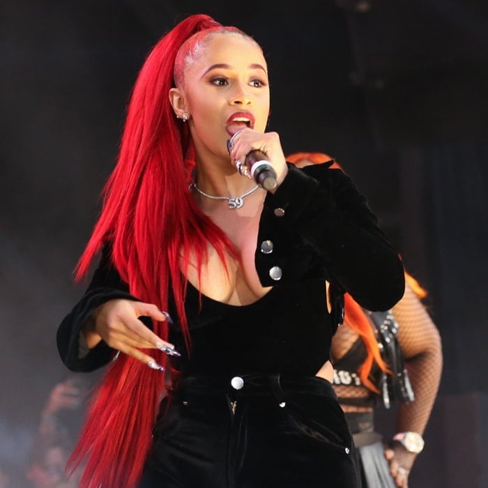 Cardi B commands the stage with vibrant red hair and a bold black outfit during a live performance