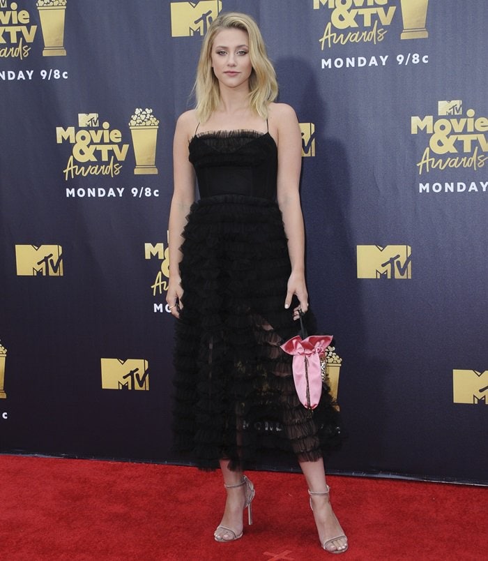 At the 2018 MTV Movie TV Awards, Lili Reinhart embraced a softer, romantic edge in a black tiered Izeta Couture dress with feminine ruffles