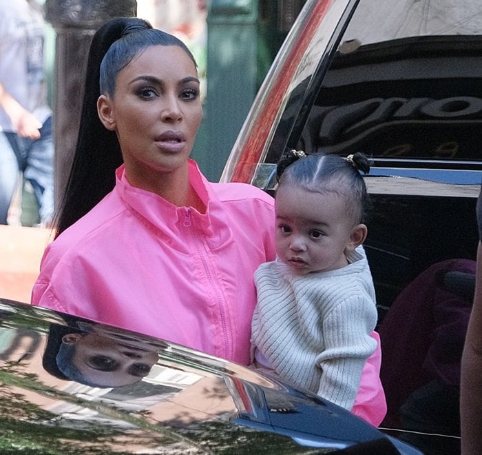 Kim Kardashian keeps the focus on color and silhouette in a high-neck pink zip jacket while holding Chicago during the family’s New York outing