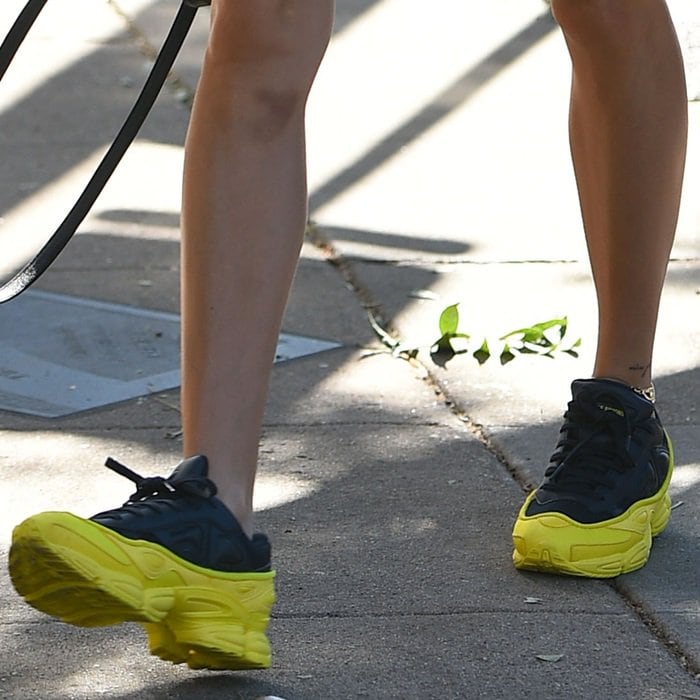 Hailey Baldwin wears navy and neon yellow Adidas by Raf Simons Ozweego sneakers