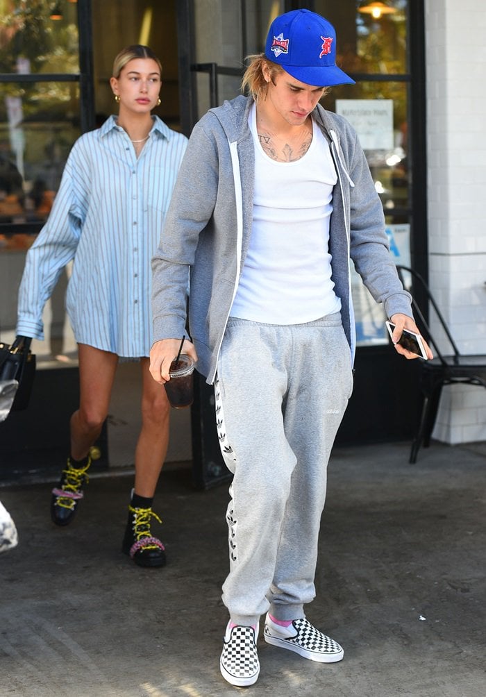 Justin Bieber steps out for breakfast at Joan’s on Third in Studio City on October 4, 2018, wearing a relaxed gray Adidas tracksuit with a white tank and classic checkerboard Vans slip-ons