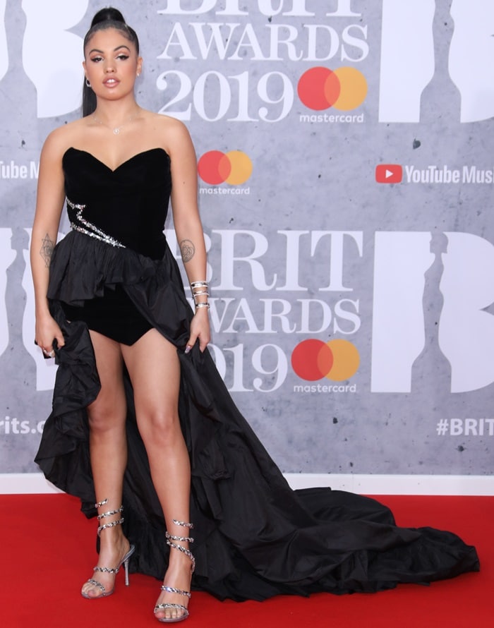 Mabel McVey turned heads at the 2019 BRIT Awards in a dramatic black Alexandre Vauthier Couture high-low gown paired with sparkling René Caovilla Cleo Maxi Strass sandals