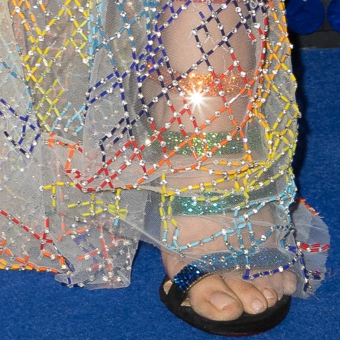 Peeking from beneath the crystal-covered gown, Christian Louboutin’s Raynibo sandals added flashes of rainbow embellishment and the brand’s signature red sole to Cheryl’s red-carpet look
