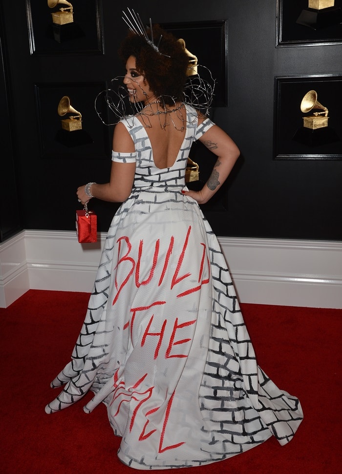 The back of Joy Villa’s voluminous white gown revealed the hand-painted “Build the Wall” slogan, transforming the sweeping train into the centerpiece of her controversial red-carpet statement.