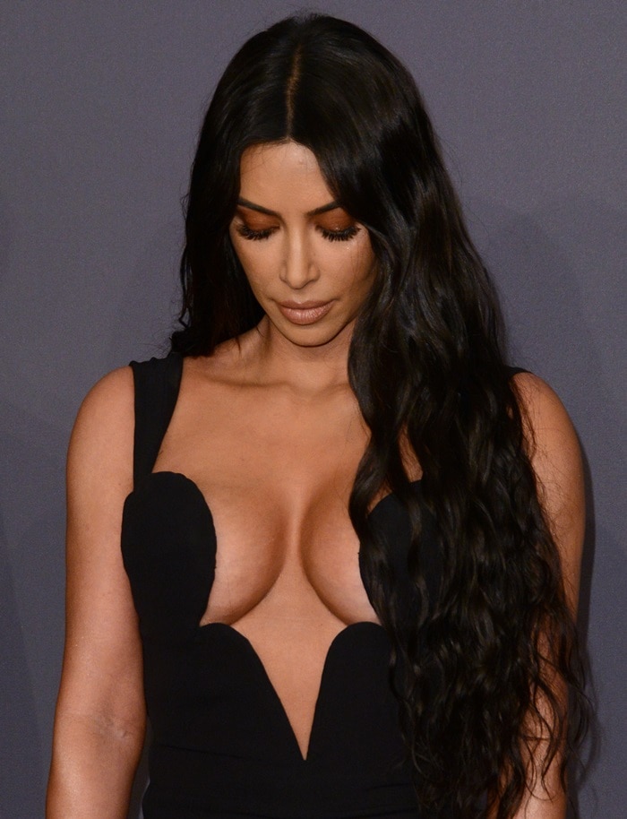Kim Kardashian showcases the daring neckline of her vintage Versace gown, secured flawlessly with fashion tape