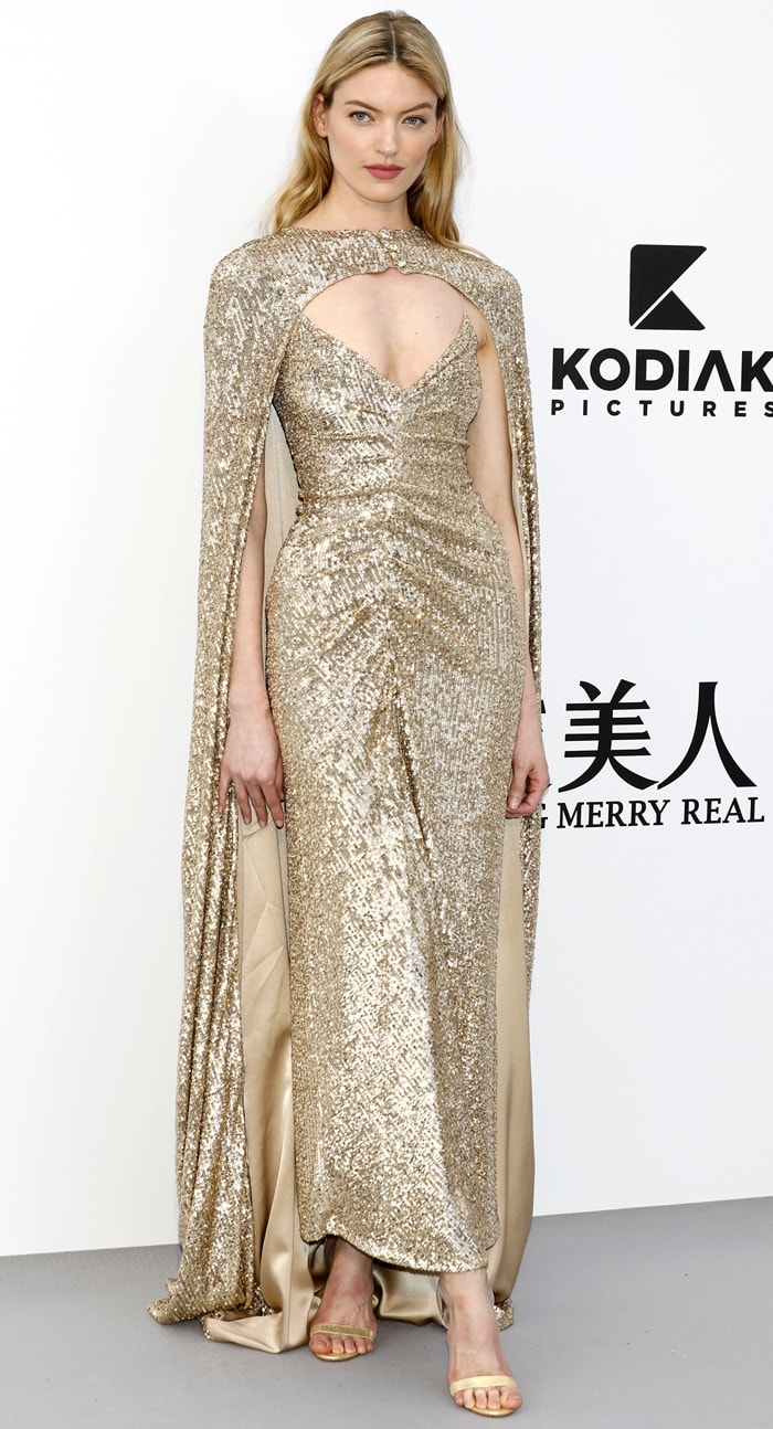 Martha Hunt dazzles in a shimmering gold Monique Lhuillier gown with a matching cape, exuding timeless glamour at the amfAR Gala during the 2019 Cannes Film Festival
