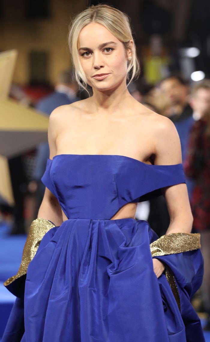 Brie Larson completed her Valentino couture look with delicate earrings by Graziela Gems and Sara Weinstock, keeping the focus on her sculptural neckline and shimmering gold cuffs