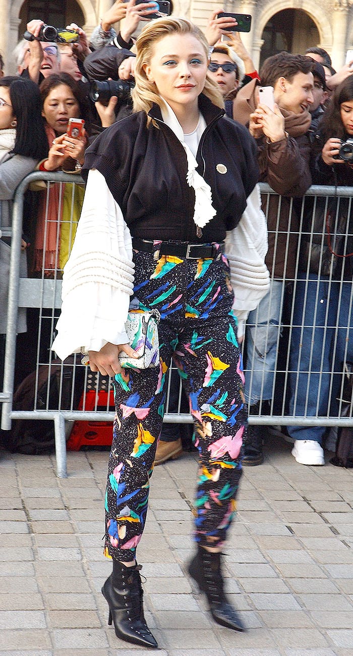 Chloë Grace Moretz in a mismatched Louis Vuitton ensemble featuring massive sleeves, colorful pants, and corset-lace-up booties