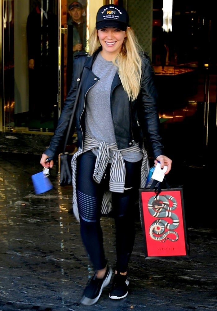 Hilary Duff exits a Gucci boutique carrying the house’s signature red shopping bag, pairing her off-duty athleisure look with a touch of unmistakable luxury branding
