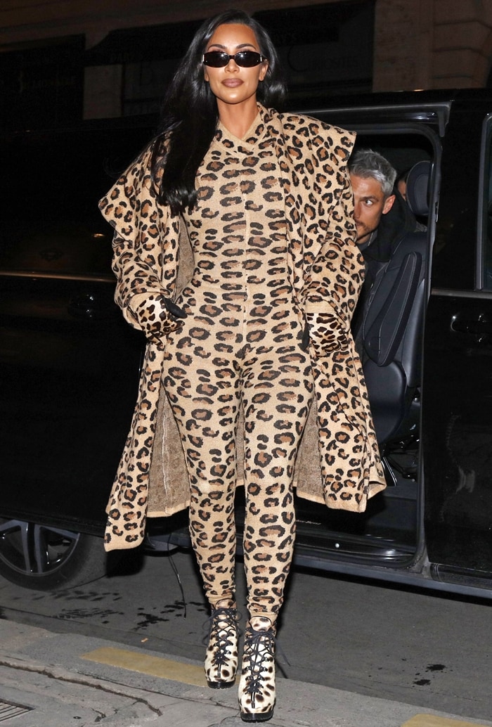 Kim Kardashian steps onto the Paris streets in a striking head-to-toe leopard look from Azzedine Alaïa’s Fall 1991 archive, pairing the sculpted bodysuit and dramatic coat with lace-up leopard calf-hair ankle boots featuring towering stiletto heels