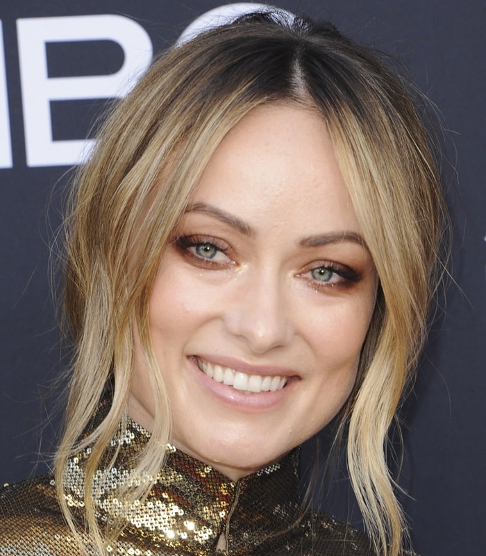 Soft bronze eye makeup and loose face-framing strands bring warmth to Olivia Wilde’s gaze, enhancing the natural green tones under bright event lighting