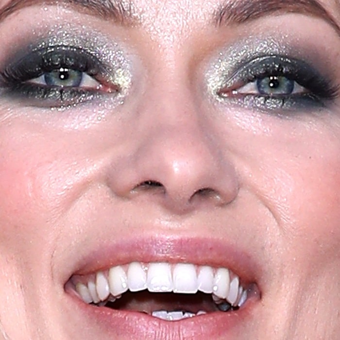 Shimmering smoky eye makeup catches the light, emphasizing a striking contrast between the inner green tones and cooler blue-gray edges of the irises